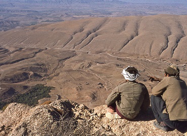 two men looking over land from the edge of a rock cliff