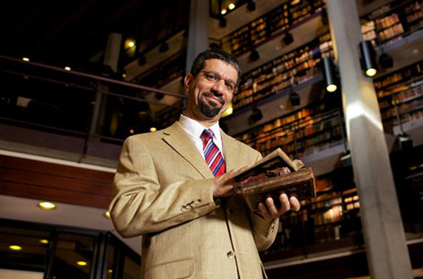 Walid Saleh holds two old books in the Fisher Rare Book Library